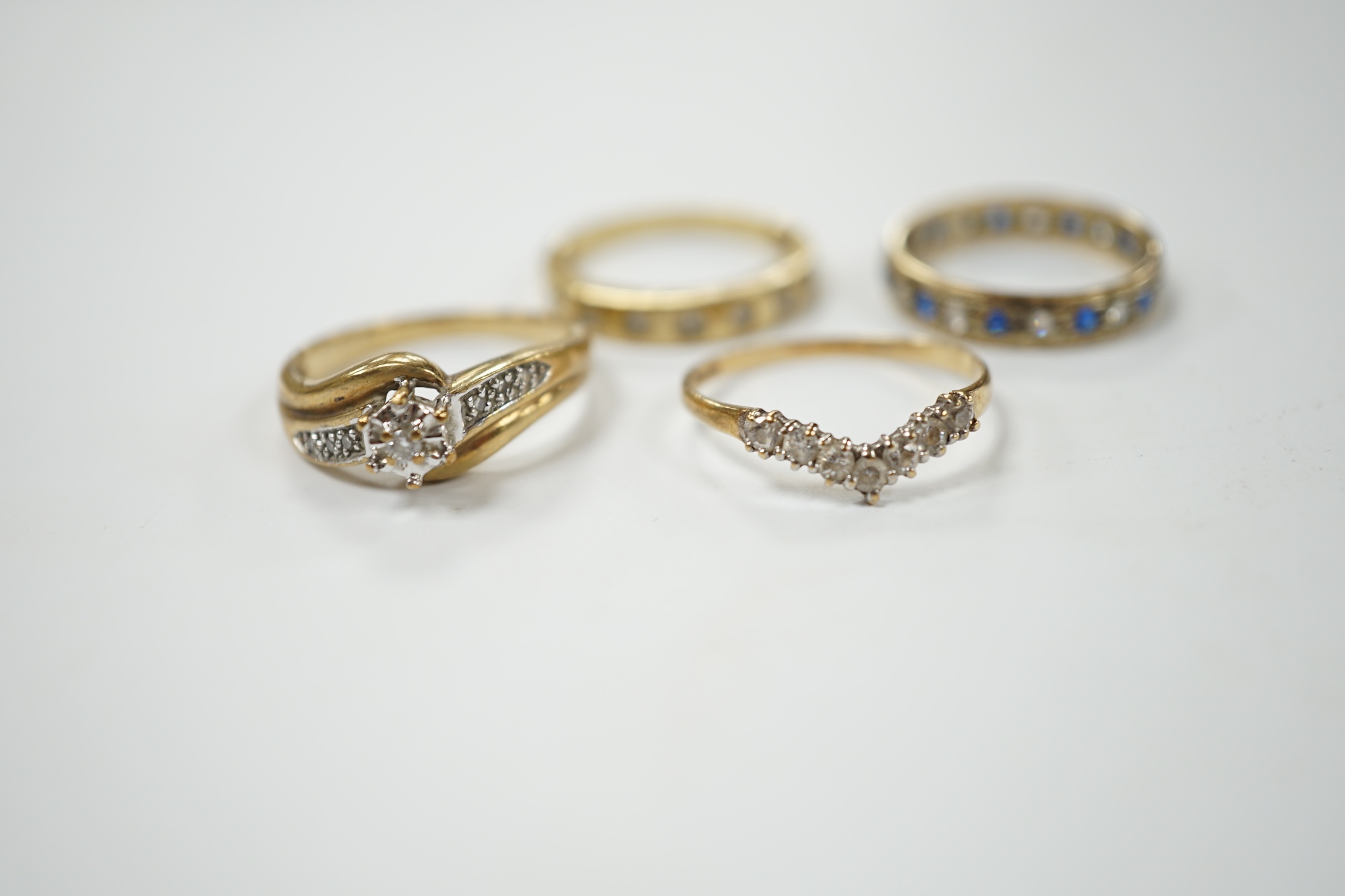 Two modern 9ct gold and diamond set rings and a 9ct gold, simulated diamond set chevron shaped ring and one other 9ct and paste set band, gross weight 9 grams. Condition - poor to fair